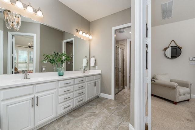 bathroom with double vanity, a shower stall, visible vents, and a sink