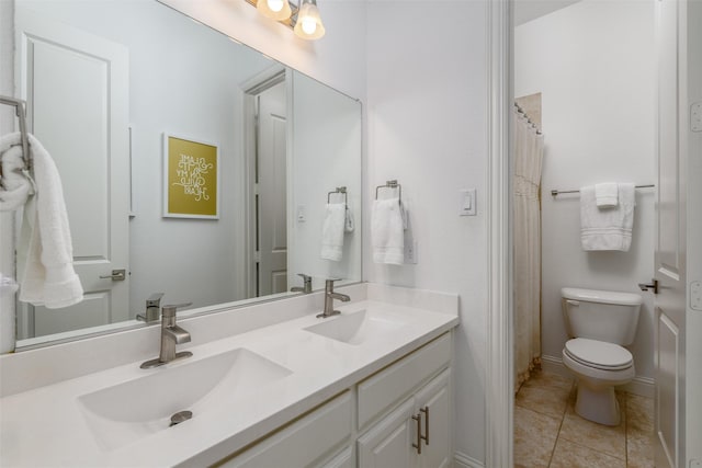 bathroom with toilet, double vanity, a sink, and tile patterned floors