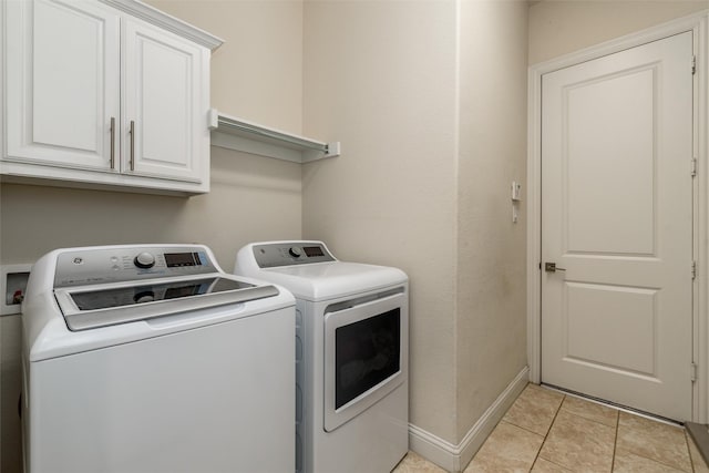 washroom with cabinet space, washer and clothes dryer, baseboards, and light tile patterned floors