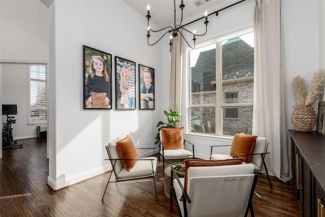 living area with a towering ceiling, dark wood-style floors, baseboards, and a chandelier