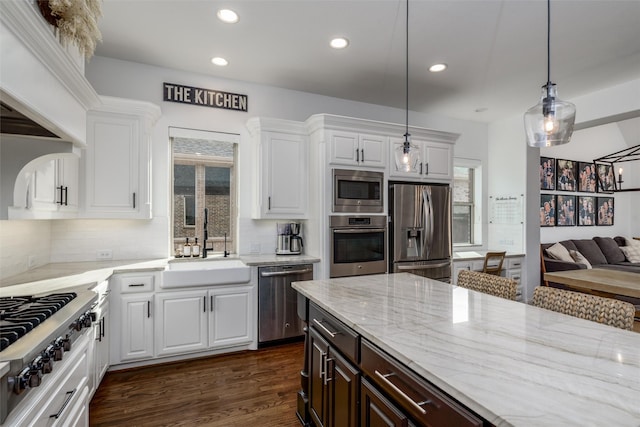 kitchen with appliances with stainless steel finishes, white cabinets, a sink, and light stone countertops