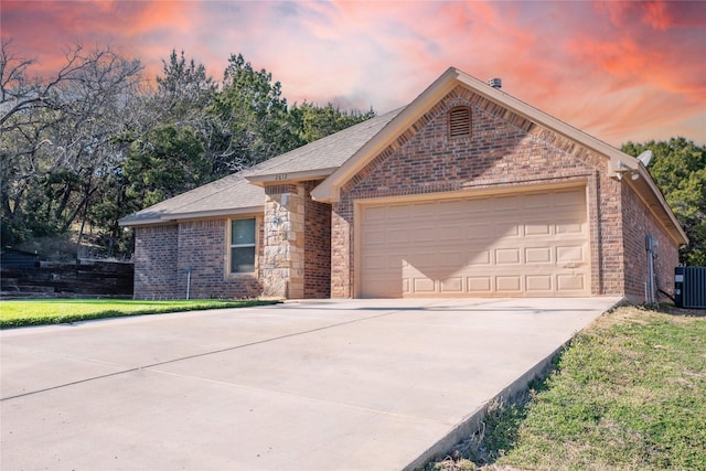 single story home with a garage, central AC, brick siding, concrete driveway, and a yard