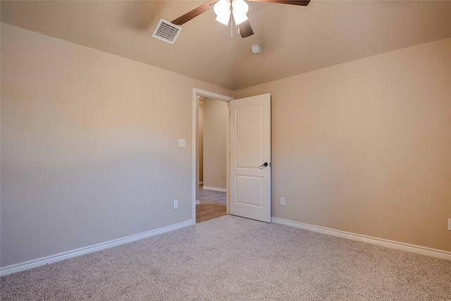 spare room featuring a ceiling fan, light colored carpet, visible vents, and baseboards