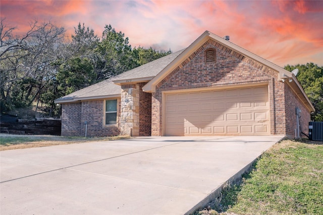 ranch-style home featuring a garage, driveway, brick siding, and central AC