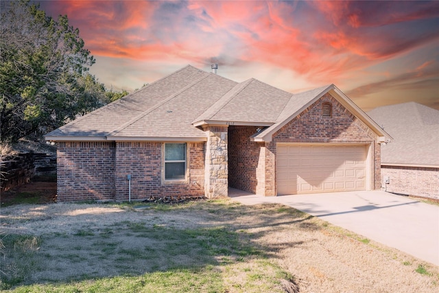 ranch-style home featuring roof with shingles, driveway, brick siding, and an attached garage