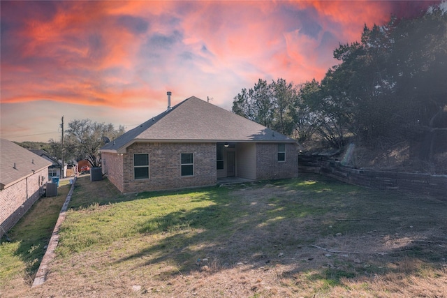 back of house with a fenced backyard, a lawn, and brick siding