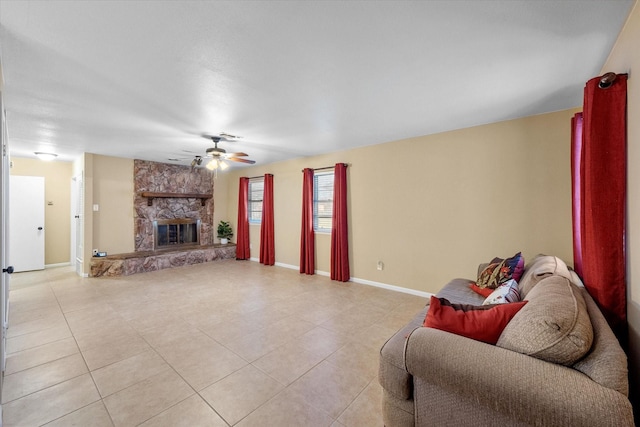 living room featuring light tile patterned floors, baseboards, ceiling fan, and a fireplace