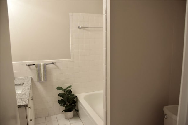 full bath featuring toilet, tile patterned flooring, a bathtub, vanity, and tile walls