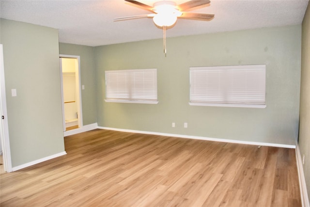 unfurnished room with a ceiling fan, a textured ceiling, baseboards, and wood finished floors