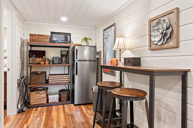 kitchen with wood ceiling, freestanding refrigerator, black microwave, and wood finished floors