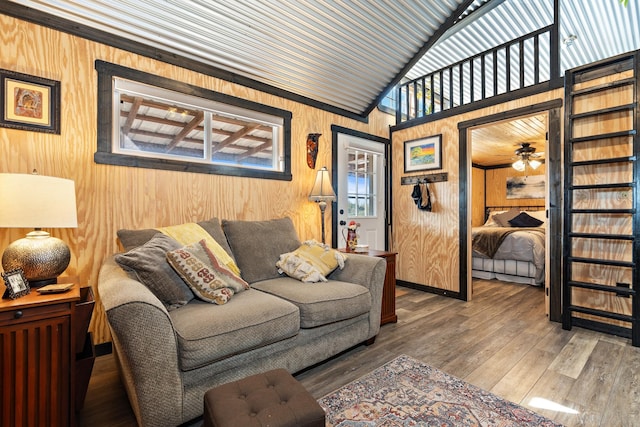 living room with wood walls, vaulted ceiling, and wood finished floors