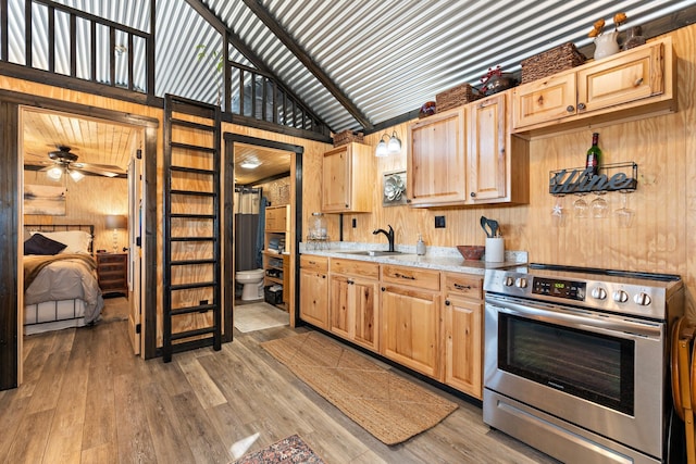 kitchen with electric stove, light countertops, a sink, and light brown cabinetry