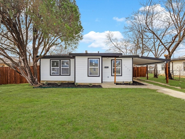 view of front of home with concrete driveway, fence, a carport, and a front yard