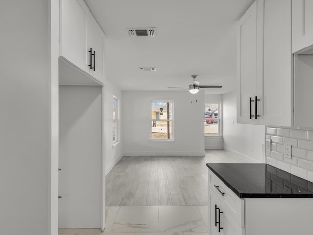 kitchen featuring tasteful backsplash, visible vents, a ceiling fan, white cabinets, and baseboards