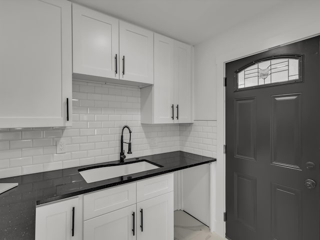 kitchen featuring a sink, white cabinets, marble finish floor, tasteful backsplash, and dark stone countertops