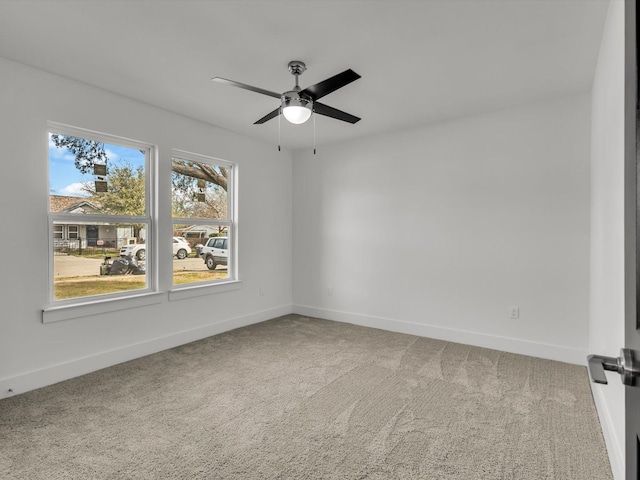 carpeted empty room featuring a ceiling fan and baseboards