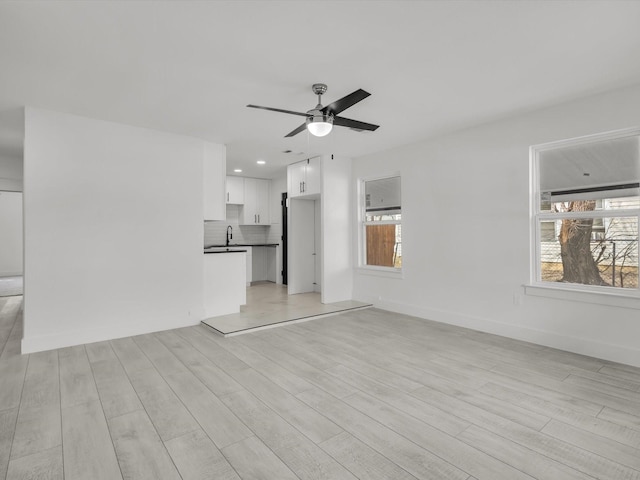 unfurnished living room with light wood finished floors, plenty of natural light, and a sink