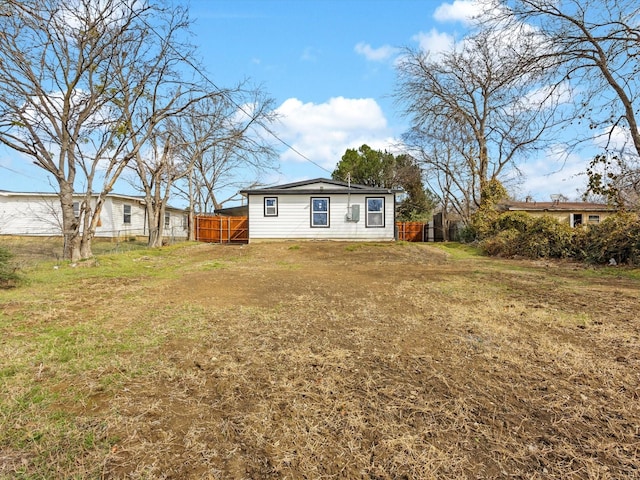 back of house featuring fence and a lawn