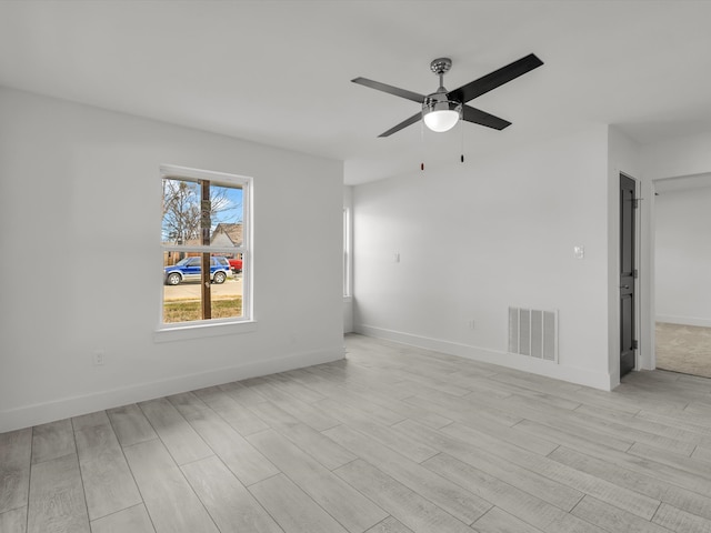 spare room with ceiling fan, light wood-style flooring, visible vents, and baseboards