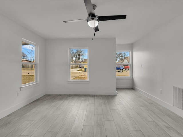 spare room with light wood-style flooring, visible vents, and a wealth of natural light