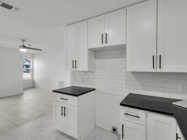 kitchen with marble finish floor, visible vents, white cabinets, and backsplash