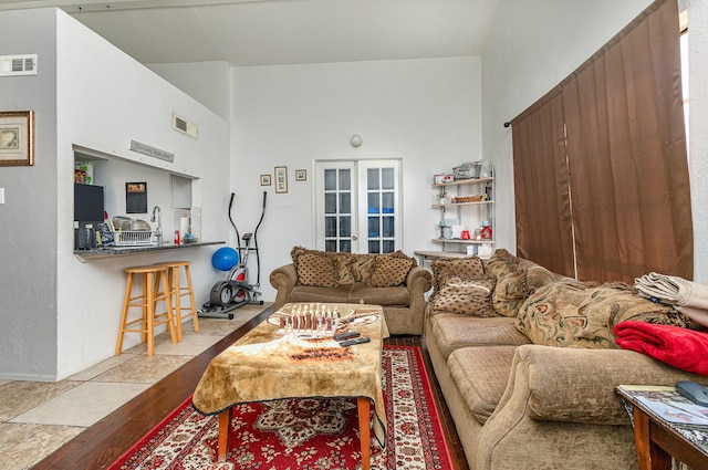 living room featuring high vaulted ceiling, french doors, wood finished floors, and visible vents