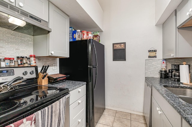 kitchen featuring under cabinet range hood, light tile patterned floors, appliances with stainless steel finishes, and decorative backsplash