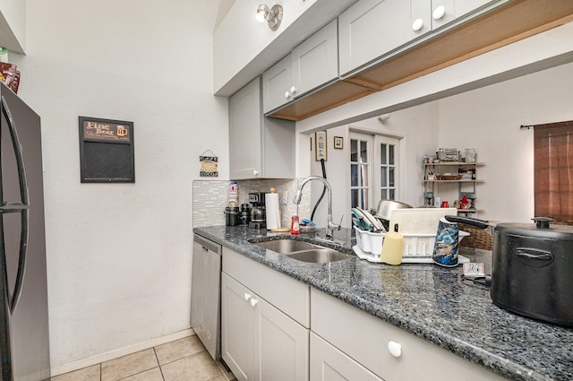 kitchen with light tile patterned floors, decorative backsplash, freestanding refrigerator, a sink, and dishwasher