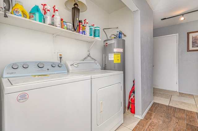 washroom featuring laundry area, light wood finished floors, baseboards, electric water heater, and washing machine and dryer