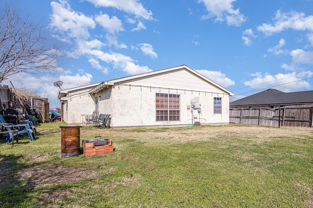 rear view of property featuring fence and a lawn