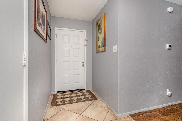 doorway featuring baseboards and a textured wall