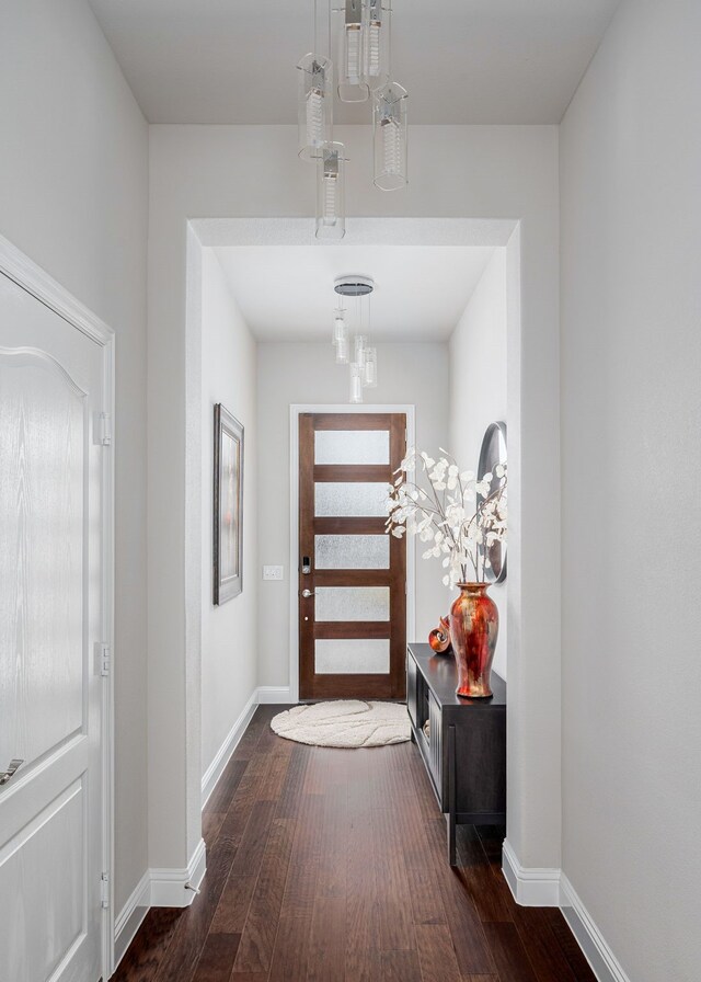 doorway featuring baseboards and wood-type flooring