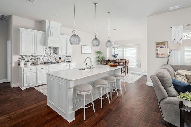 kitchen featuring visible vents, premium range hood, a sink, stainless steel gas stovetop, and open floor plan