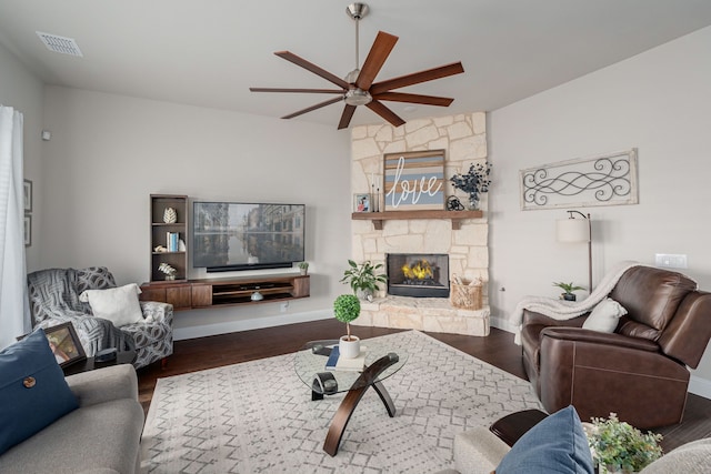 living room with wood finished floors, a ceiling fan, visible vents, baseboards, and a fireplace