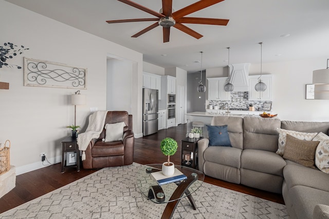 living area featuring dark wood-type flooring, a ceiling fan, and baseboards