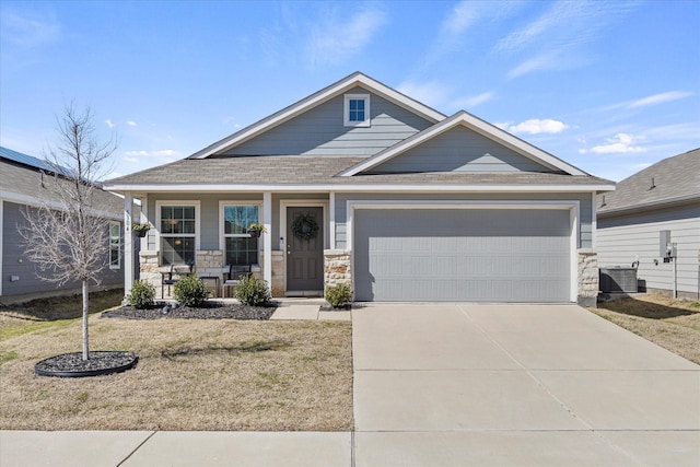 craftsman-style home featuring a porch, an attached garage, cooling unit, concrete driveway, and stone siding