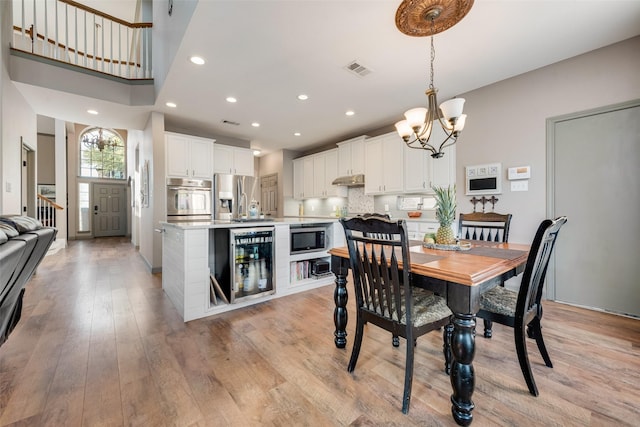 dining area with a chandelier, wine cooler, recessed lighting, visible vents, and light wood-type flooring