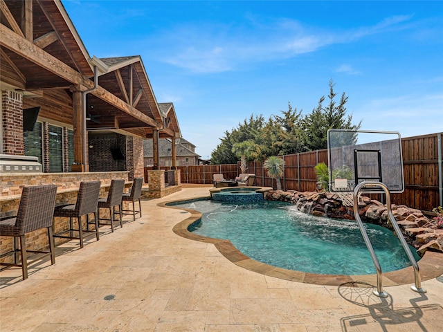 view of pool featuring a patio area, a fenced backyard, a pool with connected hot tub, and outdoor dry bar