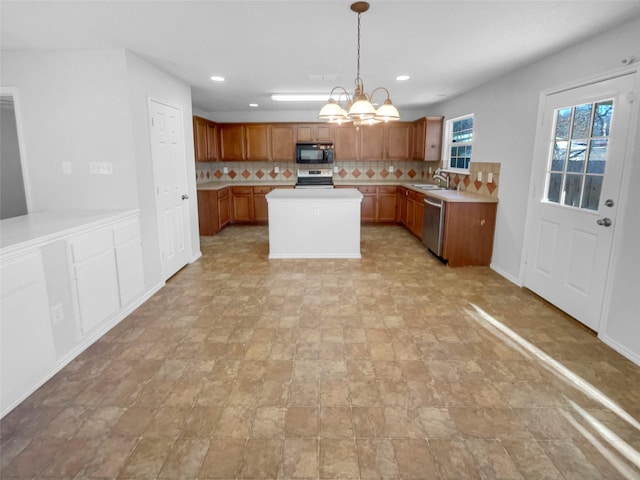 kitchen with stainless steel appliances, a sink, light countertops, tasteful backsplash, and an inviting chandelier