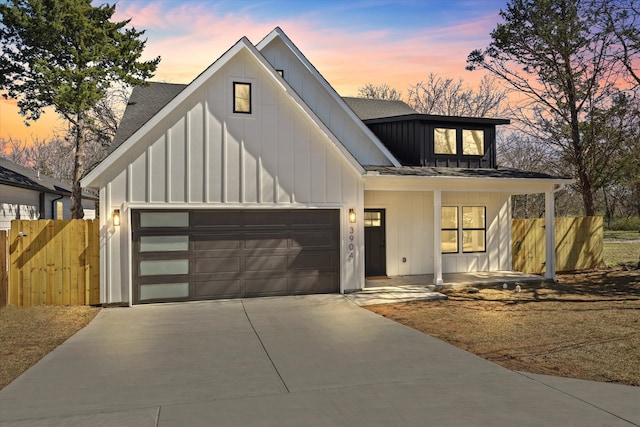 modern farmhouse style home with an attached garage, fence, board and batten siding, and concrete driveway