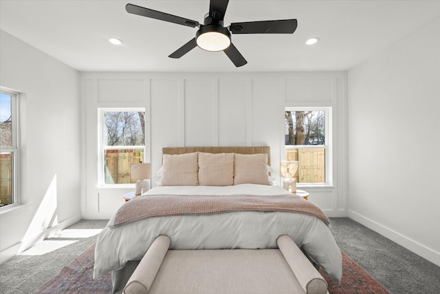 carpeted bedroom featuring multiple windows, recessed lighting, a ceiling fan, and a decorative wall