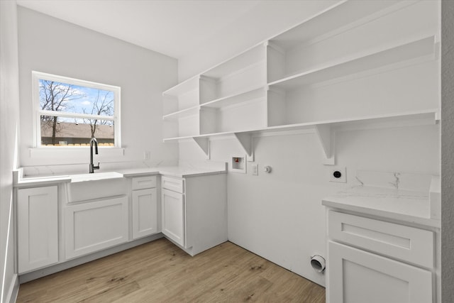 washroom with light wood finished floors, cabinet space, hookup for an electric dryer, washer hookup, and a sink