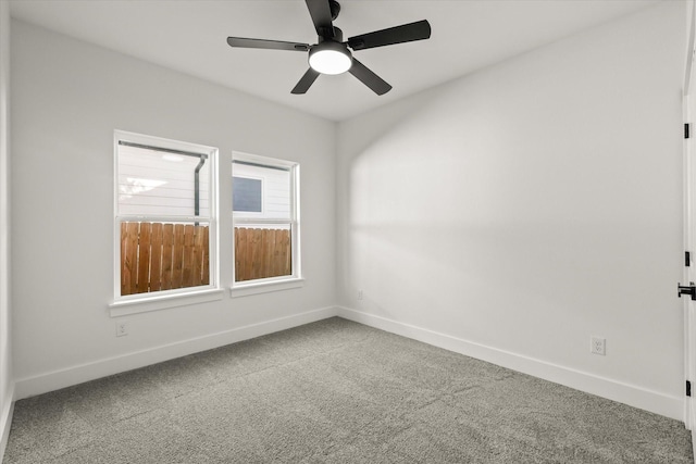 carpeted spare room featuring baseboards and a ceiling fan