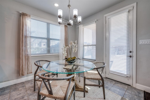 dining space with an inviting chandelier, tile patterned flooring, and baseboards