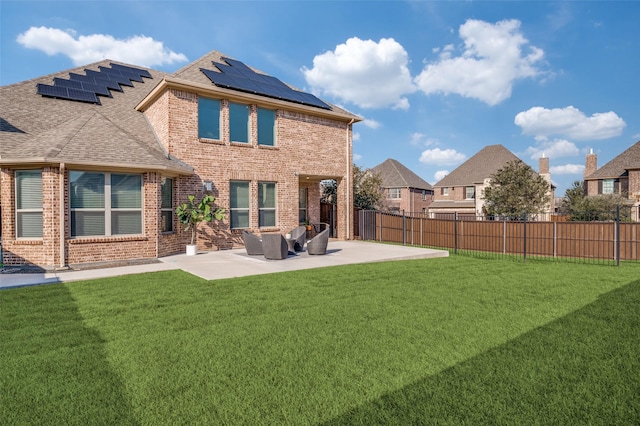 back of house with solar panels, a patio, a fenced backyard, a yard, and brick siding