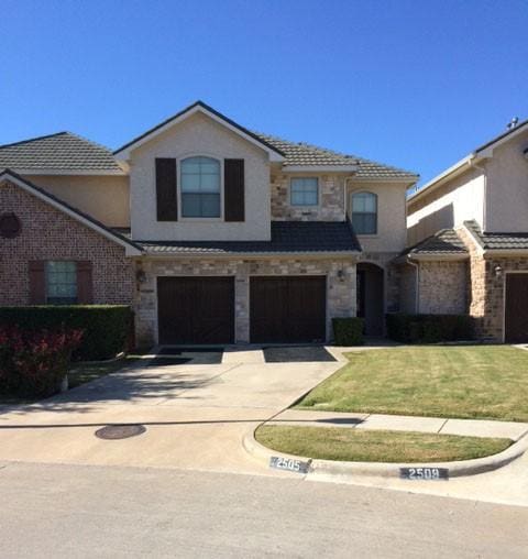 traditional-style house with stucco siding, concrete driveway, an attached garage, a front yard, and stone siding