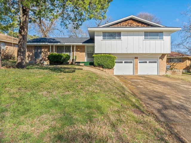 split level home with a garage, driveway, a front lawn, board and batten siding, and brick siding