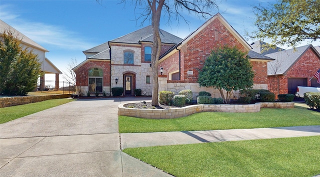 french country style house with stone siding, a shingled roof, a front yard, and brick siding