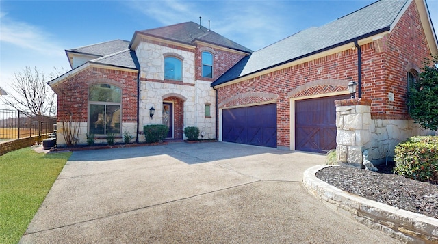 french country style house featuring an attached garage, stone siding, driveway, and brick siding