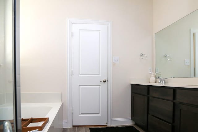 bathroom featuring a garden tub, vanity, and baseboards